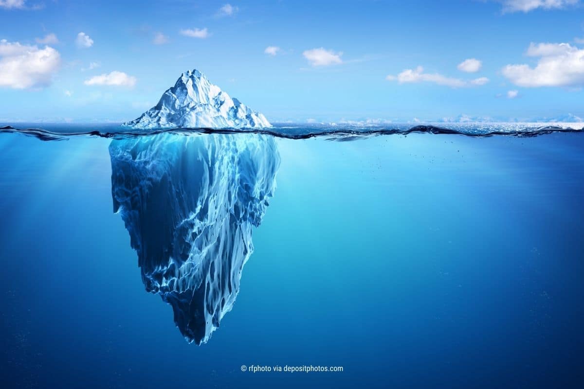 Das Bild zeigt einen Eisberg aus der Perspektive der Wasserlinie, also den sichtbaren Teil oberhalb und den unsichtbaren Teil im Wasser unterhalb. Der verrückte kumulus Jahresrückblick 2023: (Photocredit: rfphoto via depositphotos)