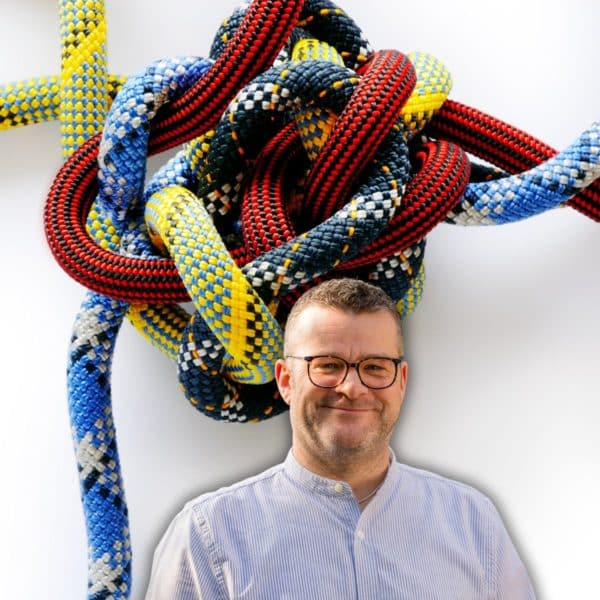 Auf dem Bild ist ein Band-Knäuel und davor Christoph Ziegler, der Systemisches Coaching anbietet. Denn ein Gordischer Knoten gehört zerschlagen!