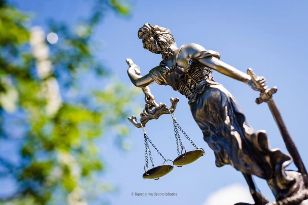 Das Bild eine Justitia-Statue von hinten vor blauem Himmel – als Metapher für Wahrnehmen ohne Wertung (Photocredit: ligorosi via depositphotos).