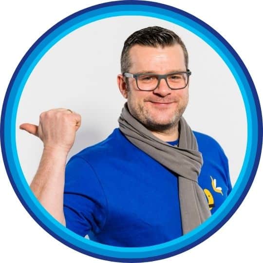 Christoph Ziegler im blauen Shirt zeigt mit dem Daumen nach links.